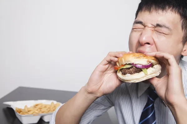 Businessman enjoying a burger — Stock Photo, Image