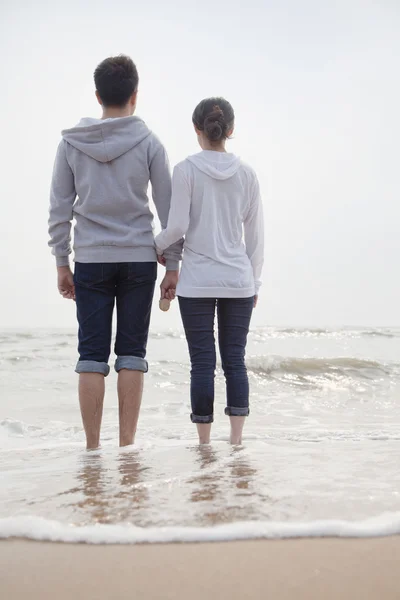 Paar steht am Strand und blickt aufs Meer — Stockfoto