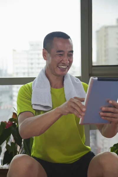 남자는 체육관에서 그의 디지털 태블릿을 보고 — 스톡 사진