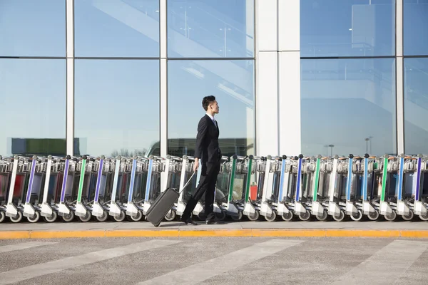Traveler next to row of luggage carts at airport — Stock Photo, Image