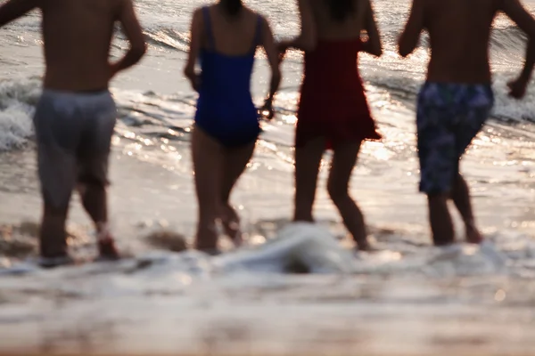 Amigos correndo para a água em uma praia de areia — Fotografia de Stock