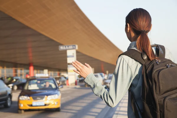 Traveler hailing a taxi at airport — Stock Photo, Image