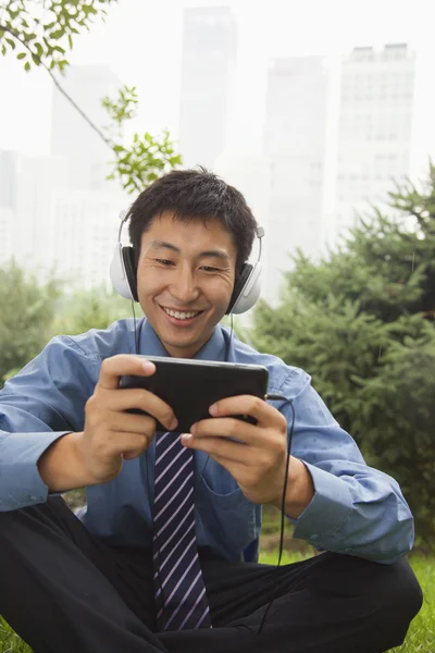 Businessman listening to music on his MP4 player — Stock Photo, Image