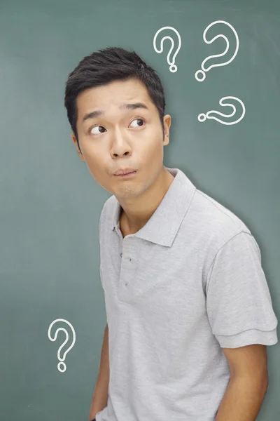 Man in front of blackboard with question marks — Stock Photo, Image