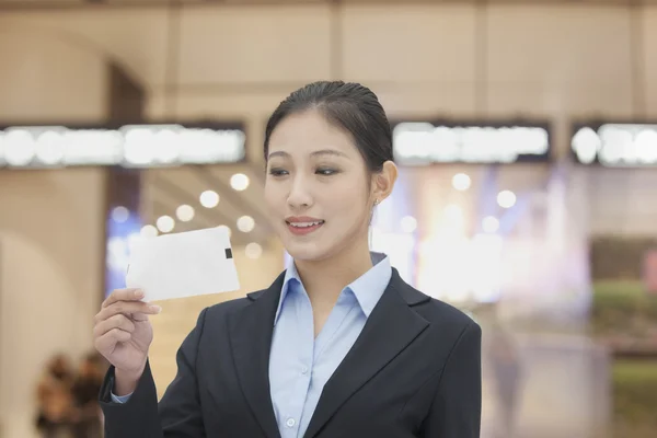 Businesswoman at the airport looking at airplane ticket — Stock Photo, Image