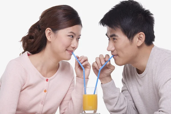 Pareja compartiendo un vaso de jugo de naranja — Foto de Stock