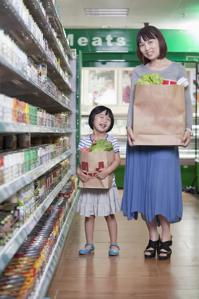 母と娘のスーパー マーケットで食料品の袋を保持しています。 — ストック写真