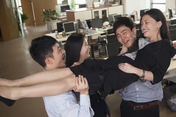 Pessoas de negócios se divertindo carregando colega de trabalho — Fotografia de Stock