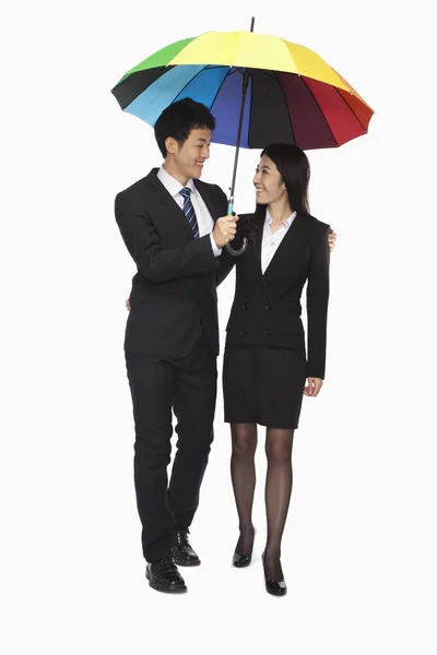 Homme d'affaires et femme d'affaires marchant sous un parapluie coloré — Photo