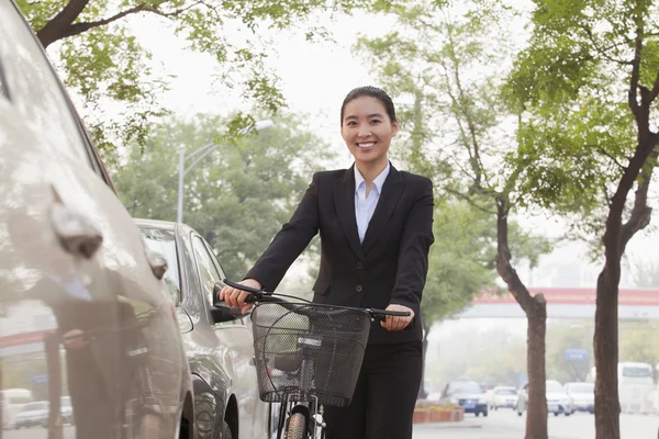 Businesswoman holding a bicycle on the street — Stock Photo, Image