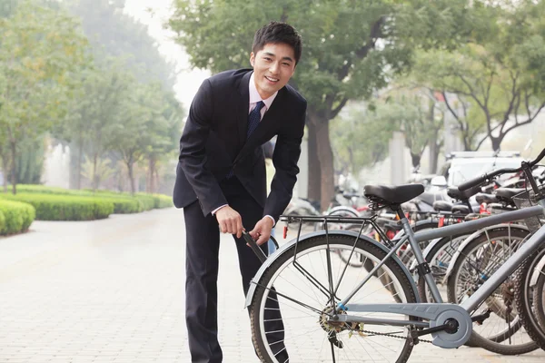 Biznesmen zatrzaskiwanie w górze jego rower na ulicy miasta — Zdjęcie stockowe