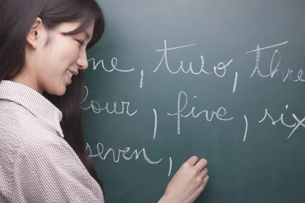 Woman student writing English numbers — Stock Photo, Image