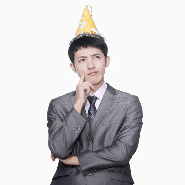 Businessman thinking, wearing party hat — Stock Photo, Image