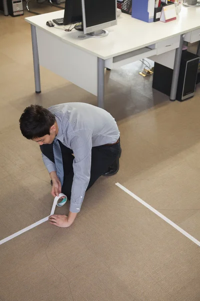 Businessman taping up the floor in the office — Stock Photo, Image