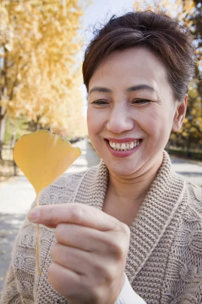 Зрелая женщина с жёлтым листом гинкго — стоковое фото