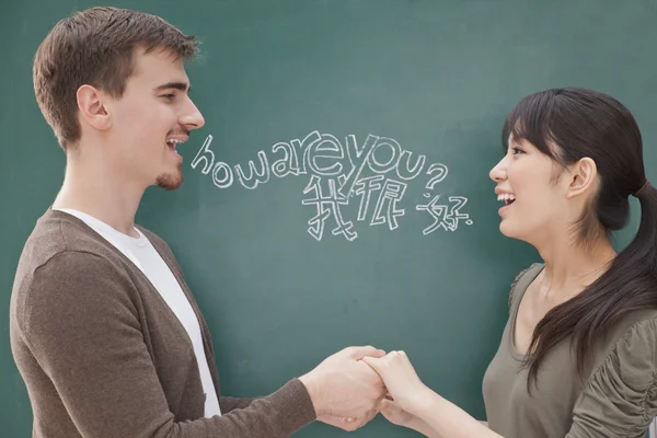 Teacher and student in front of chalkboard holding hands Stock Image