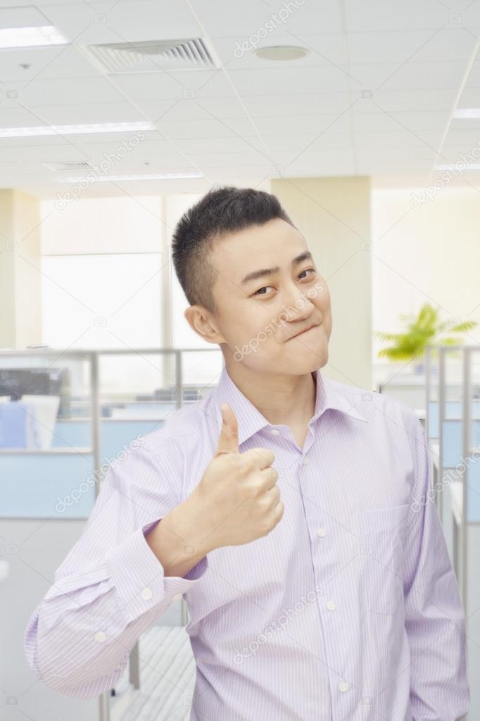 Man giving thumbs up sign in office