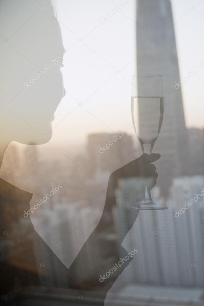Woman toasting with champagne flute over cityscape