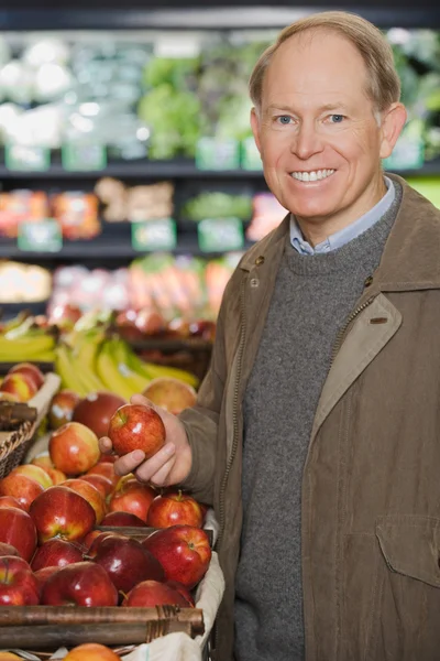 Man met een appel in winkel — Stockfoto