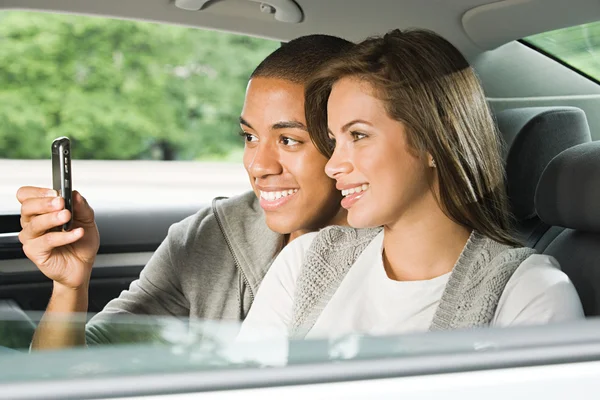 Pareja usando el teléfono celular en el coche — Foto de Stock