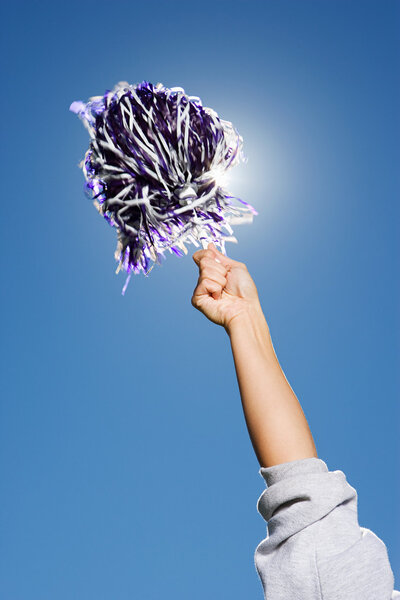 Arm of cheerleader holding pom-pom