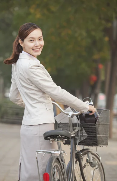 Mujer de negocios de pie con una bicicleta —  Fotos de Stock