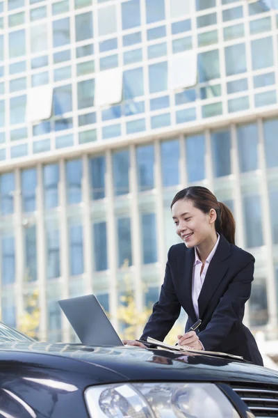 Affärskvinna stående med bil med laptop — Stockfoto