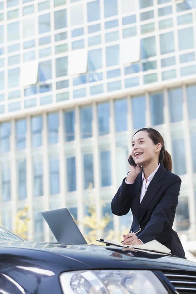 Affärskvinna stående med bil med telefonen — Stockfoto