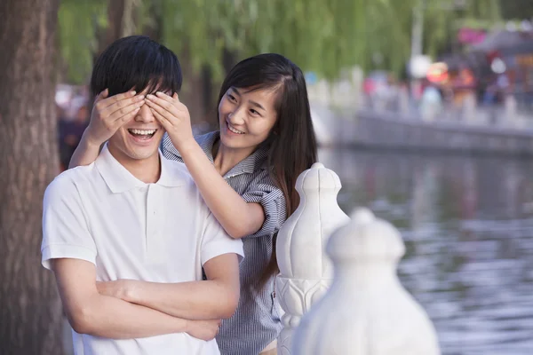 Mujer cubriendo ojos de hombre por un lago —  Fotos de Stock