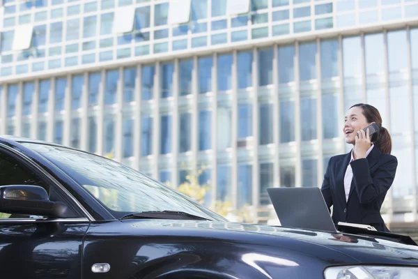 Femme d'affaires debout en voiture au téléphone — Photo