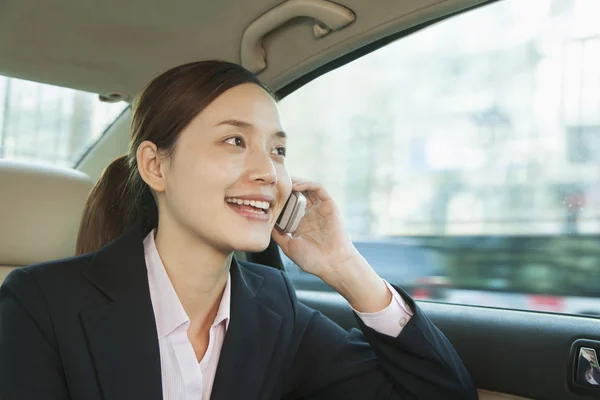 Empresária no banco de trás do carro no telefone — Fotografia de Stock