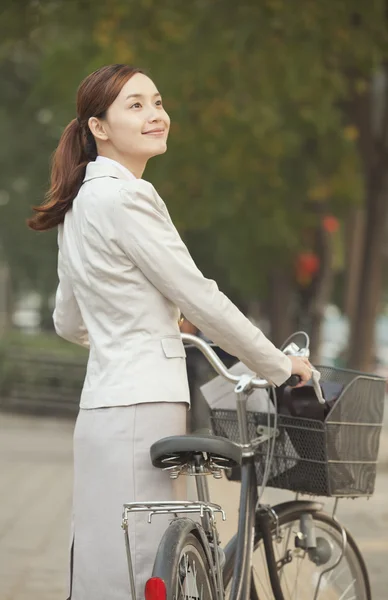 Mujer de negocios de pie con una bicicleta —  Fotos de Stock