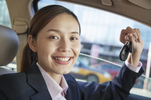 Femme d'affaires assis dans la voiture, montrant les clés — Photo