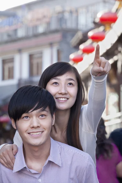 Pareja joven señalando al aire libre — Foto de Stock