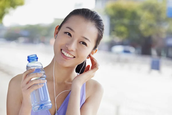 Nő, palackozott víz közben zenét hallgatni — Stock Fotó