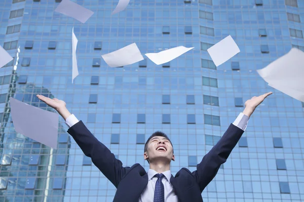 Affärsman kasta papper med armar i luften — Stockfoto
