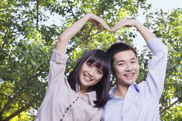 Pareja haciendo una forma de corazón con sus brazos — Foto de Stock