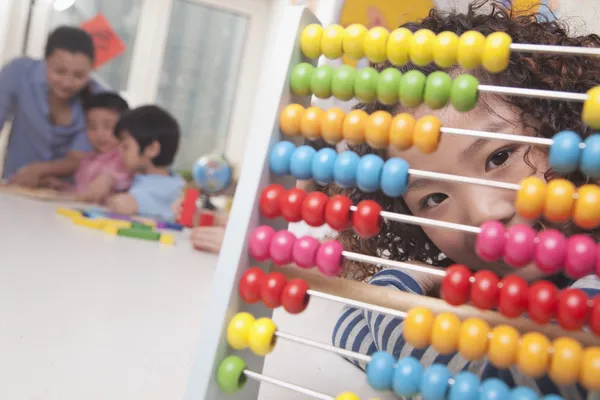 Liten flicka tittar genom abacus — Stockfoto