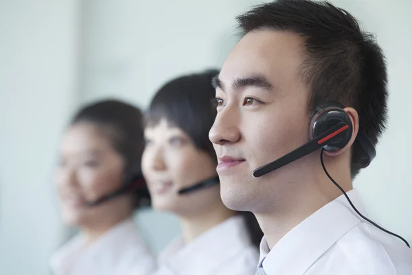 Tres trabajadores de cuello blanco en una fila con auriculares — Foto de Stock