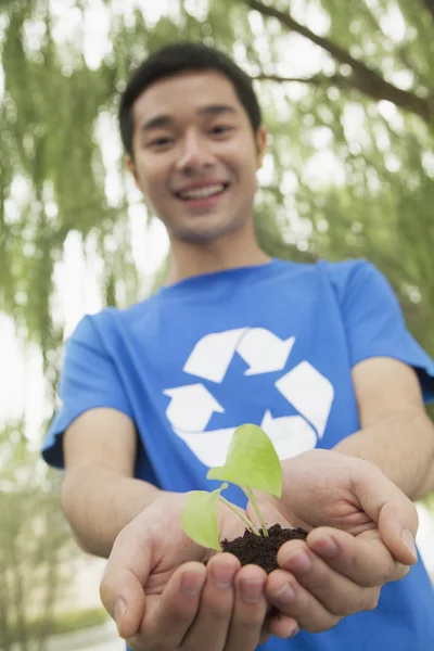 Ung man håller plantan i hans händer — Stockfoto