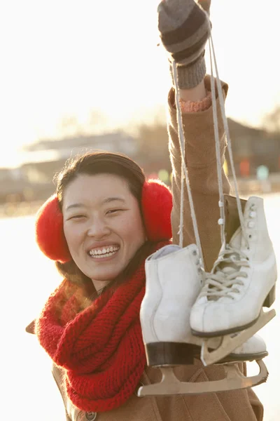 Frau hält draußen Schlittschuhe hoch — Stockfoto