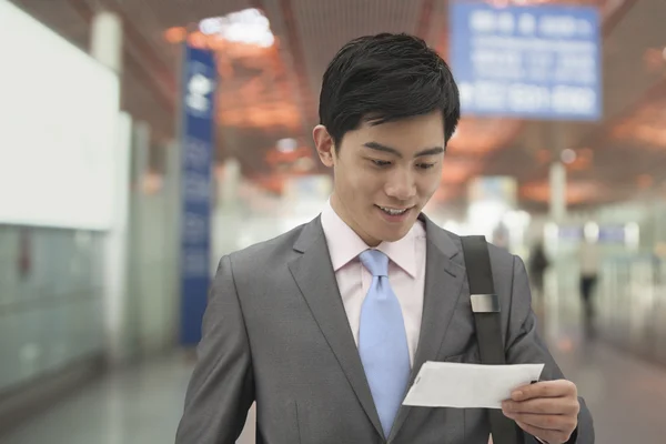 Un om de afaceri se uită la un bilet la aeroport — Fotografie, imagine de stoc