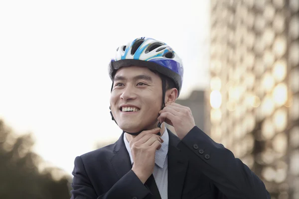 Businessman putting on cycling helmet — Stock Photo, Image
