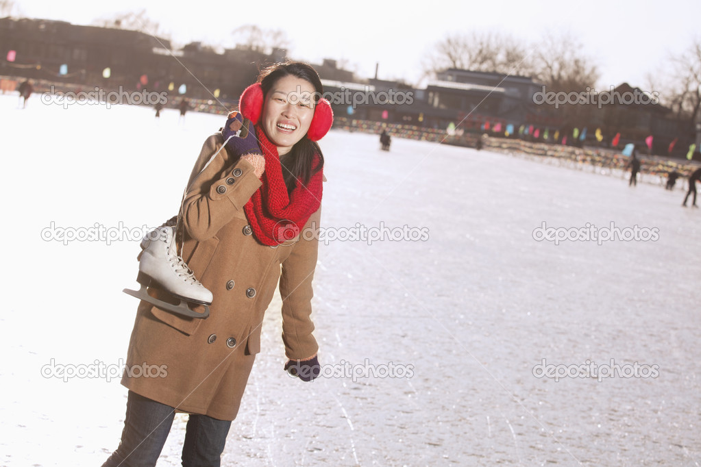 Woman Holding Up Ice Skates Outside