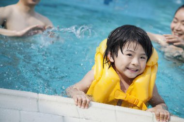 Smiling son in the water with family in the background clipart