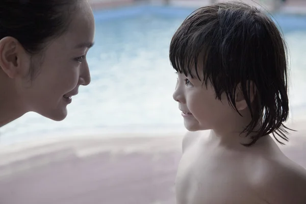 Madre e figlio faccia a faccia vicino alla piscina — Foto Stock