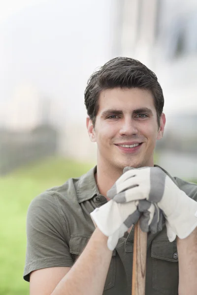 Man holding a rake on a roof top garden in the city — Stock Photo, Image