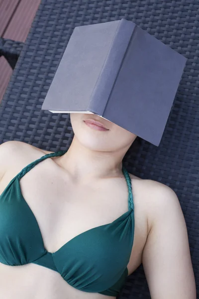 Frau entspannt sich mit einem Buch über dem Gesicht — Stockfoto