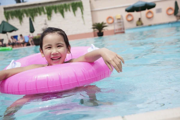 Mädchen schwimmt im Pool mit einem rosa Schlauch — Stockfoto