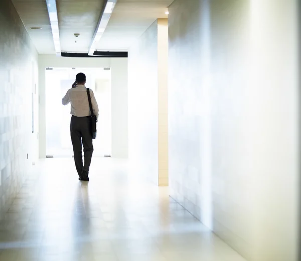 Affärsman gick ner i korridoren på telefonen — Stockfoto